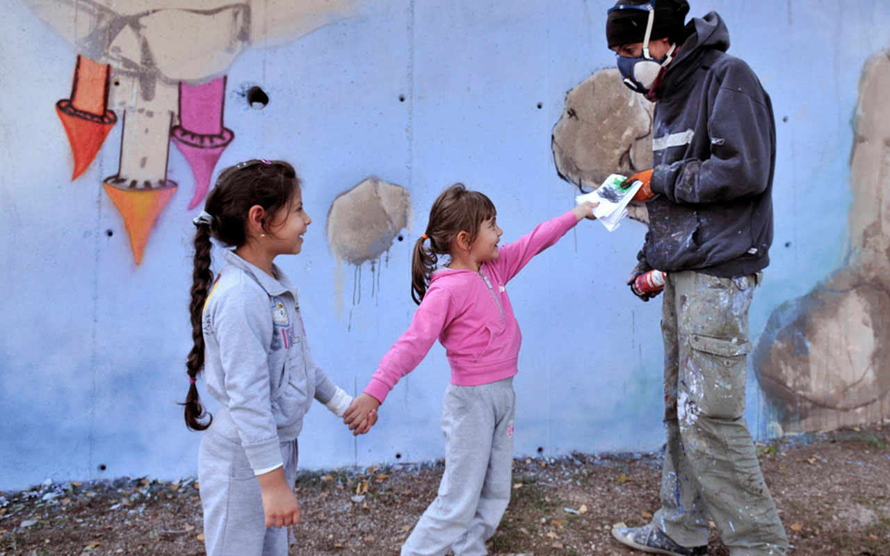 a man is painting a wall with two little girls