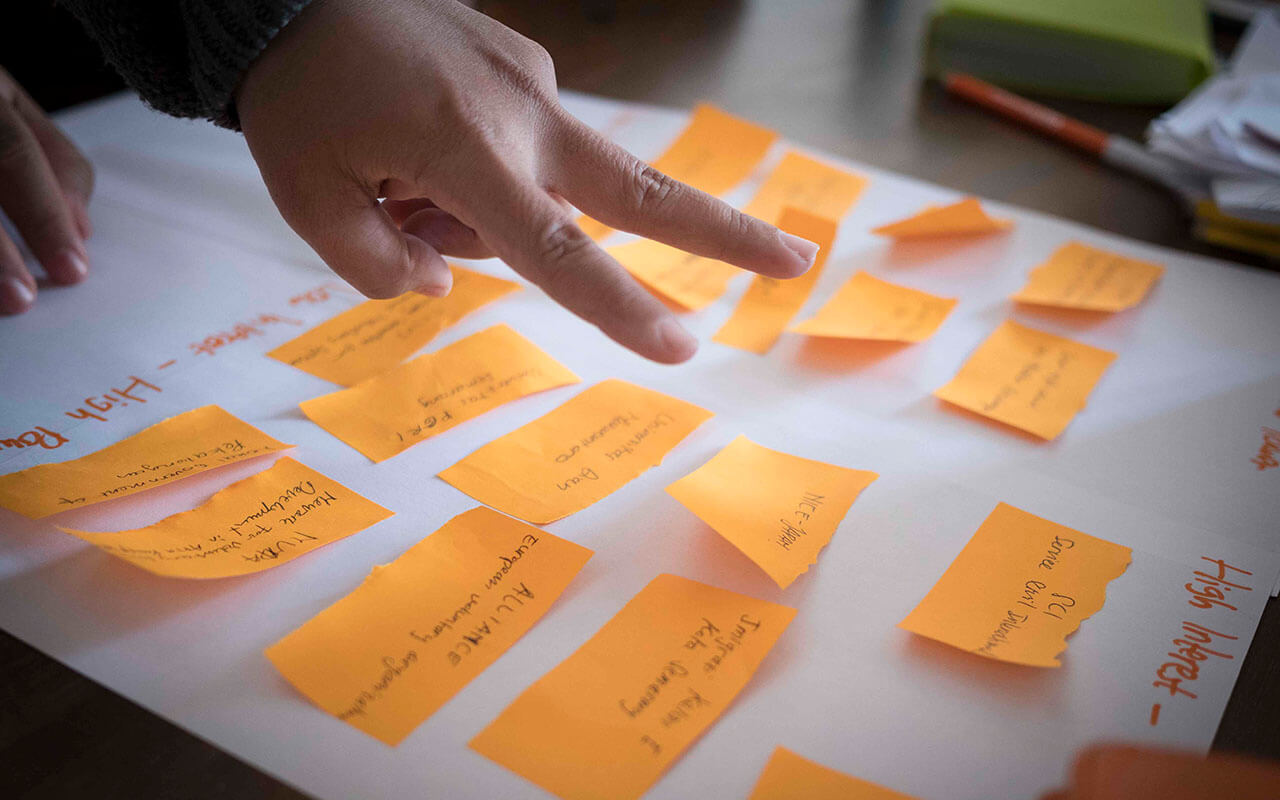 a person pointing at sticky notes on a sheet of paper